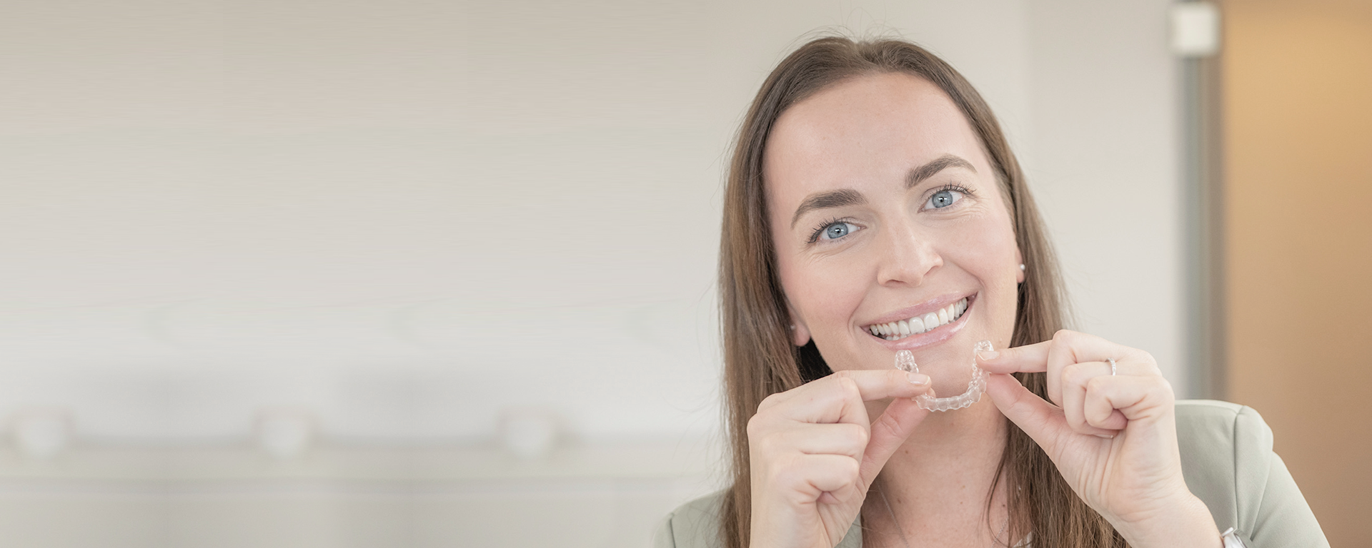 Lächelnde Frau mit transparenter Zahnschiene in der Hand