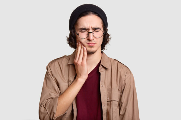 Junger Mann mit Zahnschmerzen nach Füllung